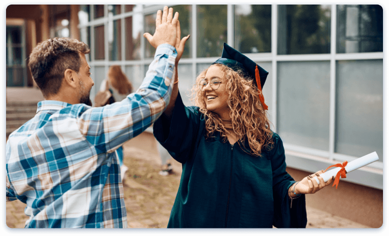 students high fiving at graduation